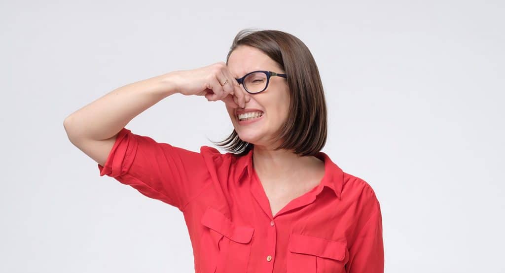 woman plugging nose because of sewer smell