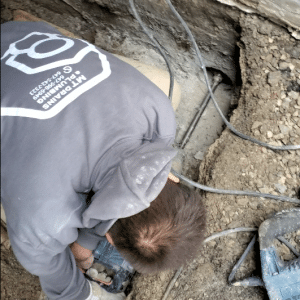 plumber drilling trench drain connection
